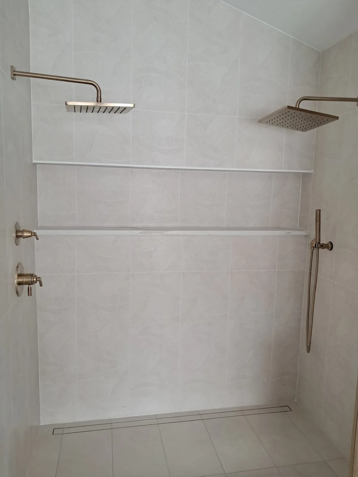 Marble-look shower with two gold rain showerheads